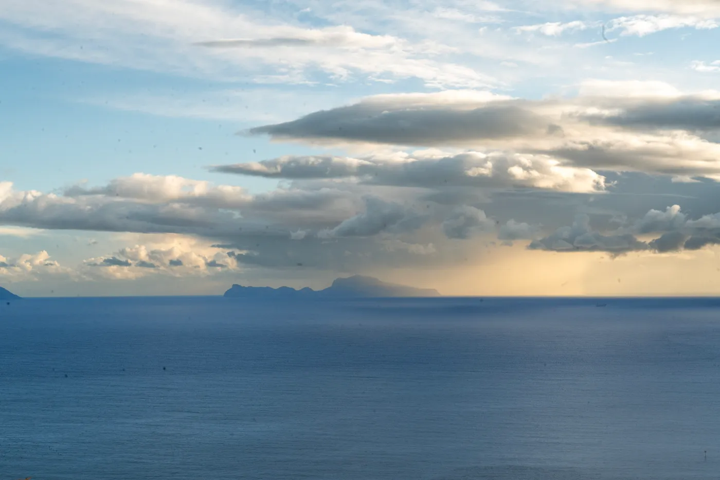 Capri on the horizon, rain hanging under the clouds.