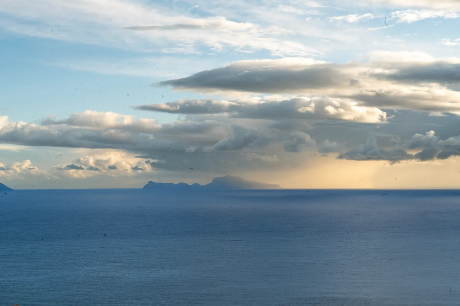 Capri on the horizon, rain hanging under the clouds.