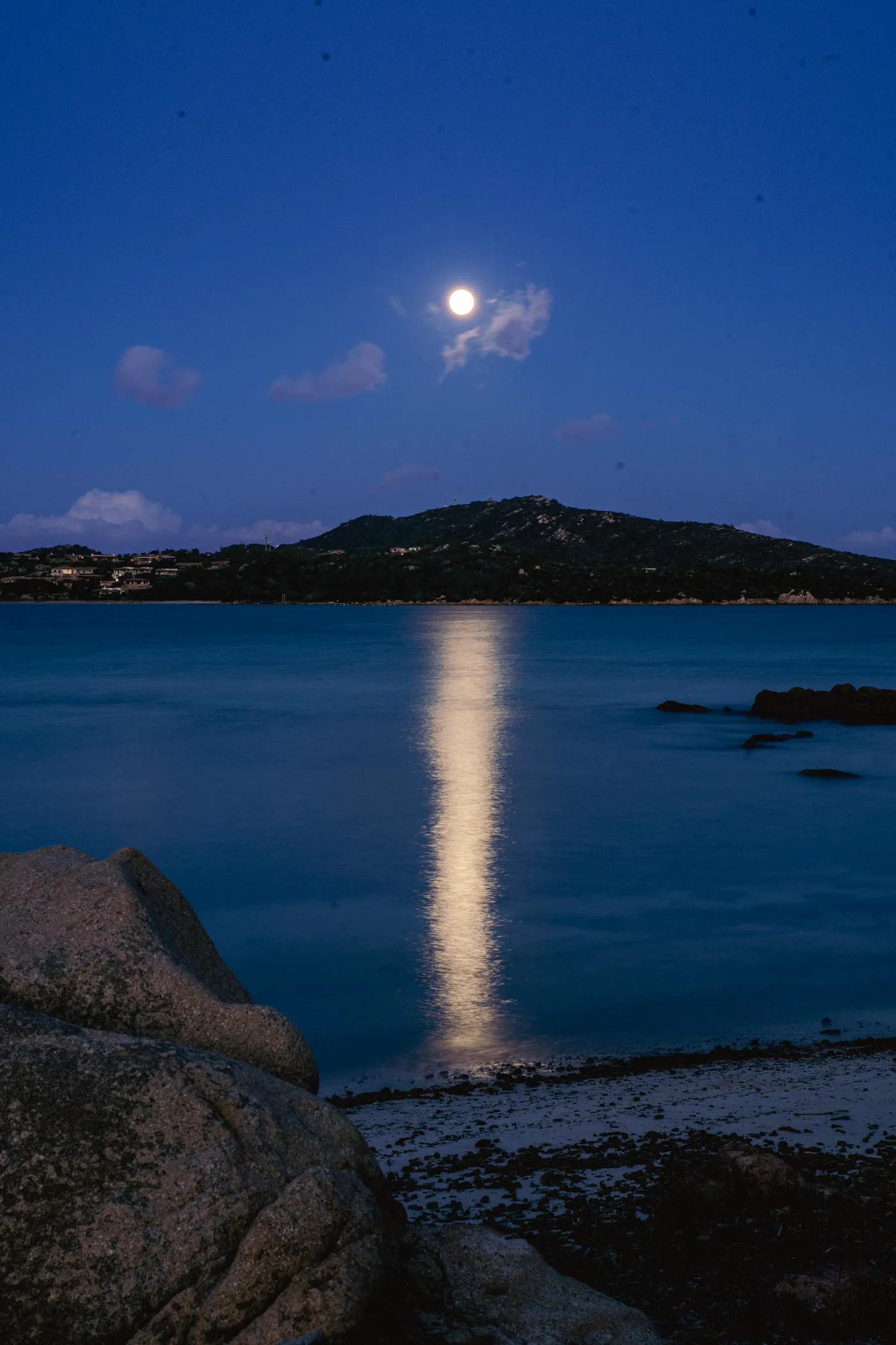 Full moon over the bay, granite in the foreground.