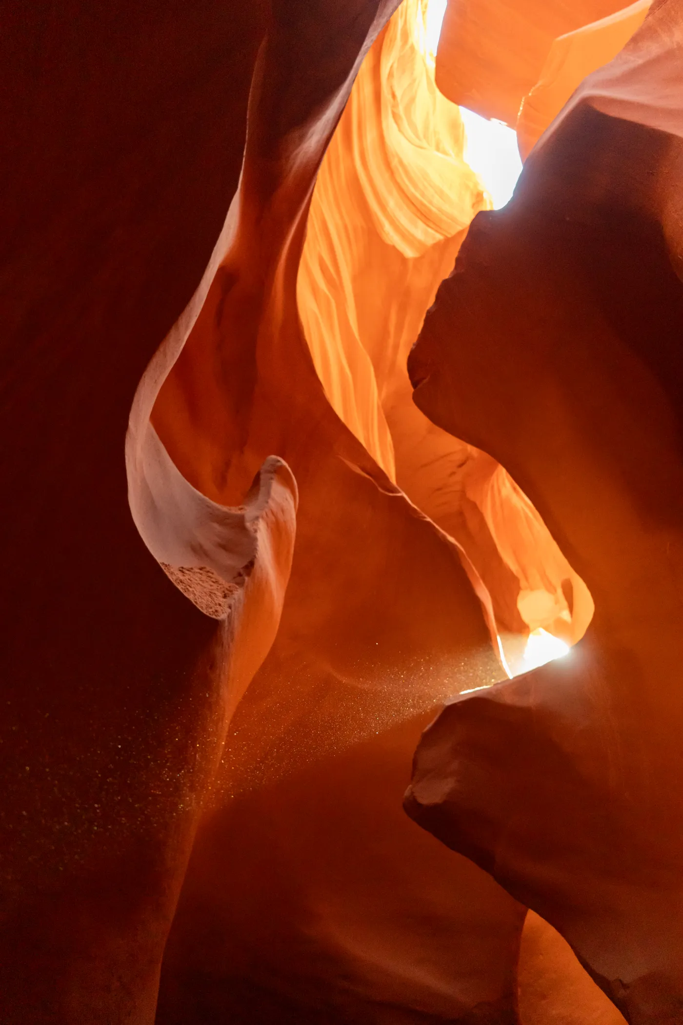 A shaft of light reaching the floor, sand poured from above to catch it.