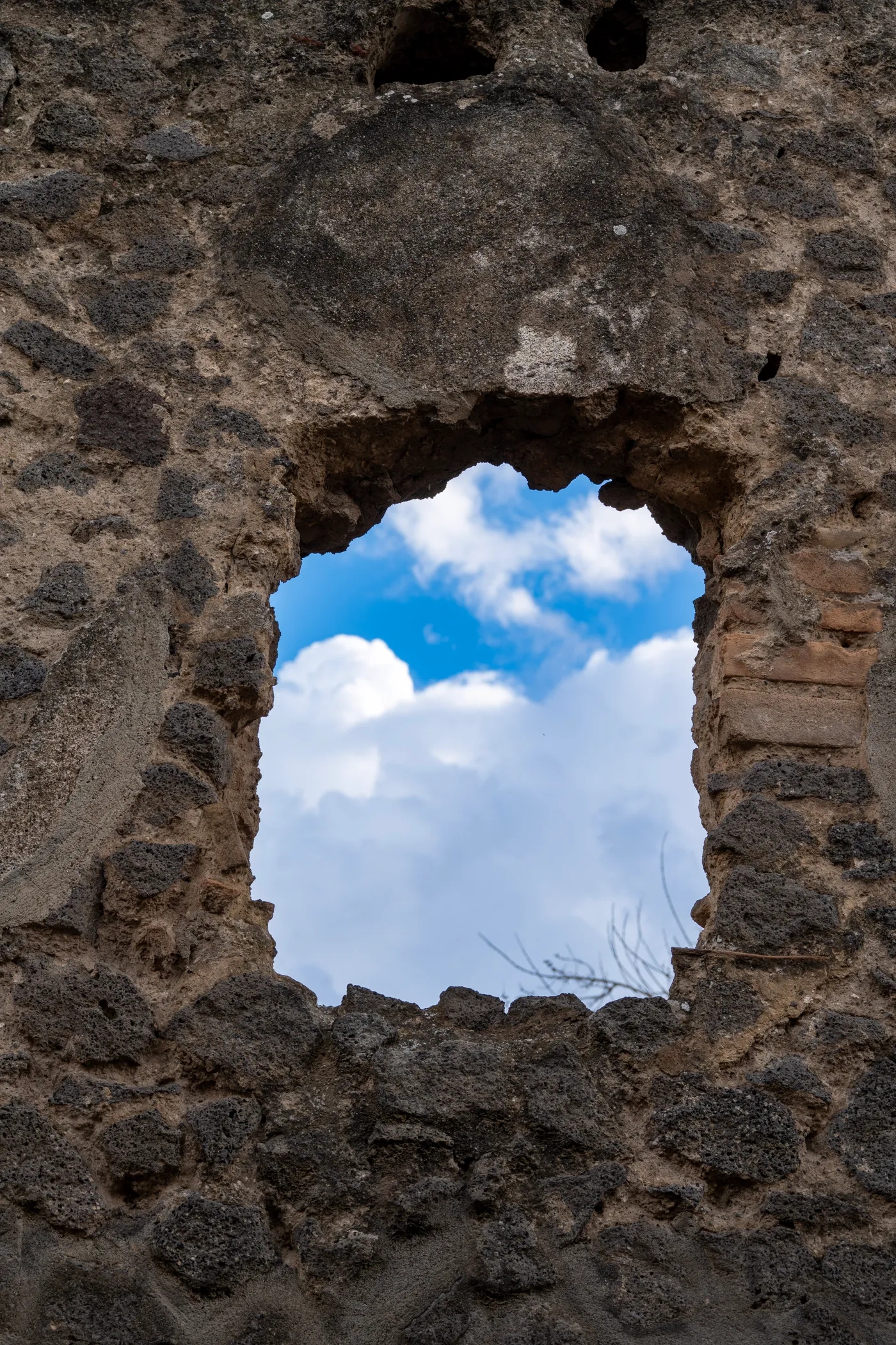 Sky through a window in a wall of lava stone in Pompei.